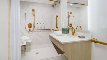 A modern bathroom with a white sink, gold fixtures, and a marble shower wall.