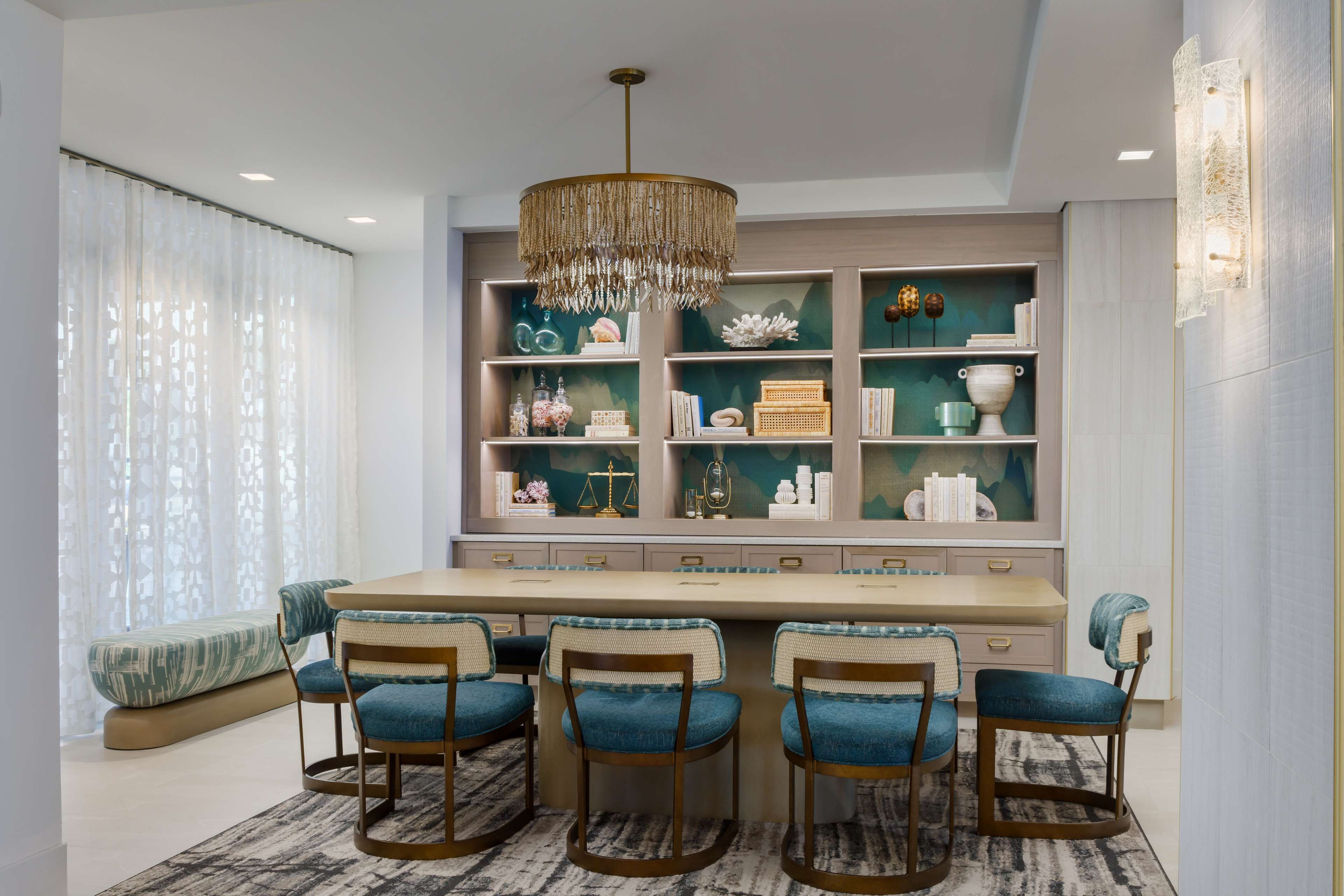 Un espace repas comprenant une longue table, quatre chaises et un lustre.