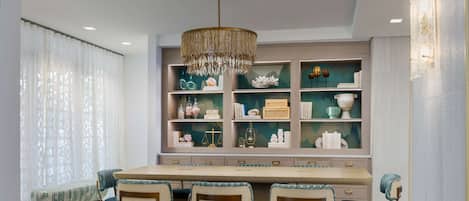 Un espace repas comprenant une longue table, quatre chaises et un lustre.