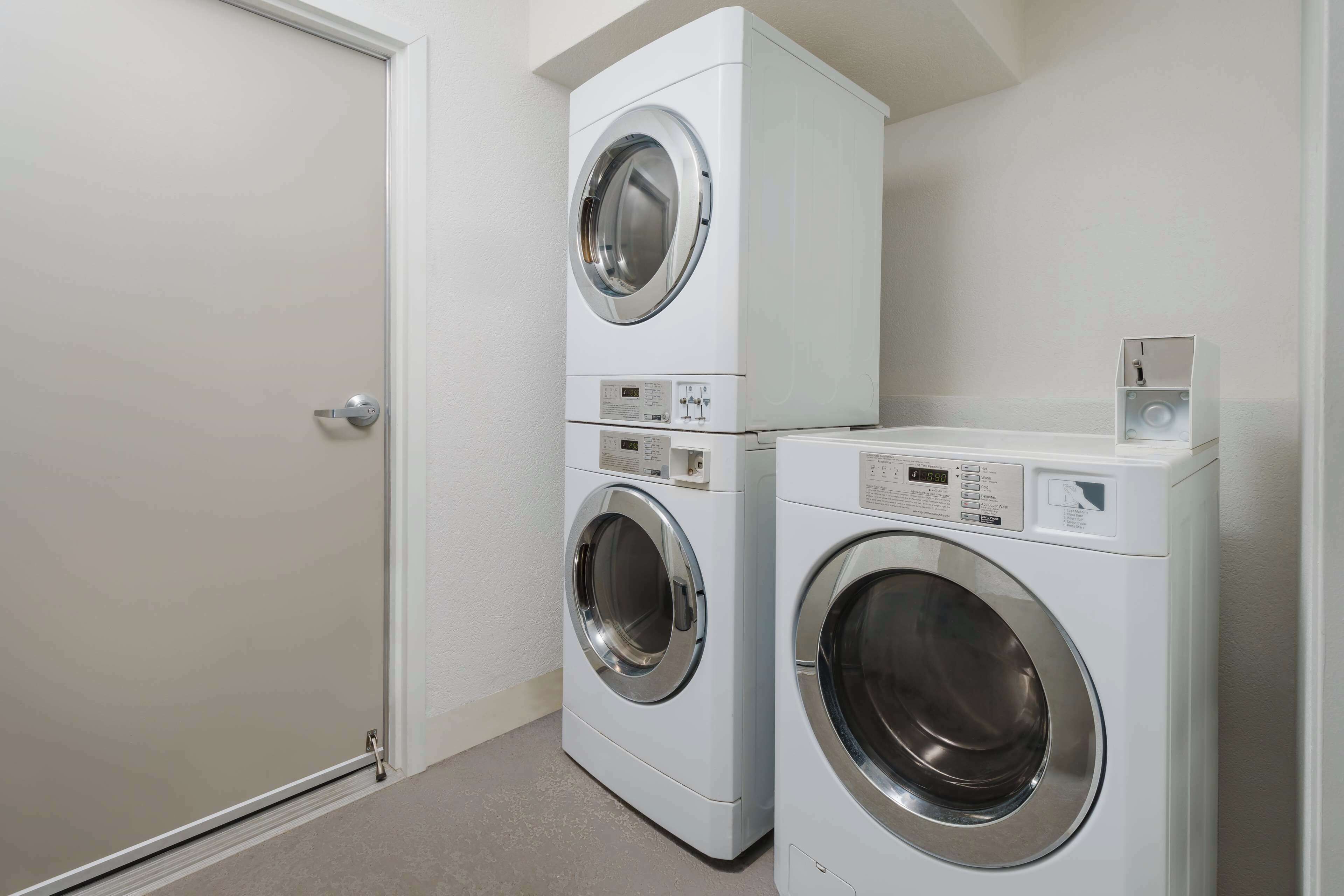 A laundry room with two stacked front-loading washing machines and a closed door.