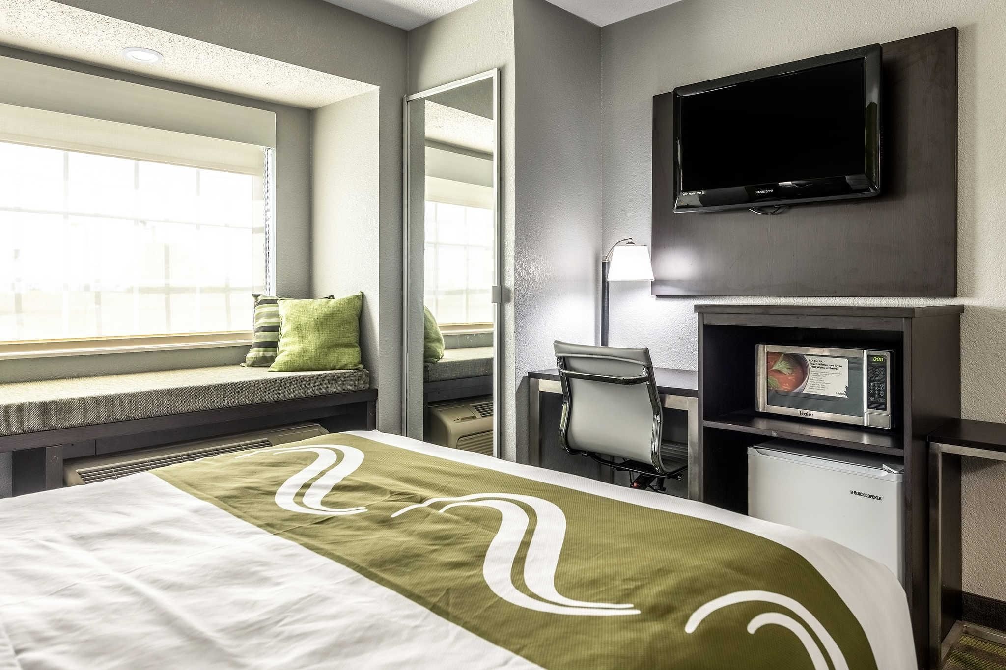Ein Hotelzimmer mit Bett, Schreibtisch, Fernseher und Mikrowelle.