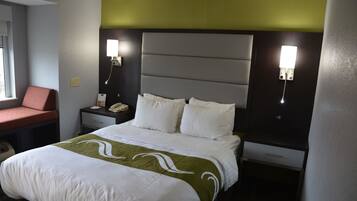 Une chambre d’hôtel comprenant un lit, une table de chevet avec un téléphone et un bureau avec une chaise.
