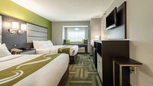 Habitación de hotel con dos camas, un escritorio, un televisor y una ventana.