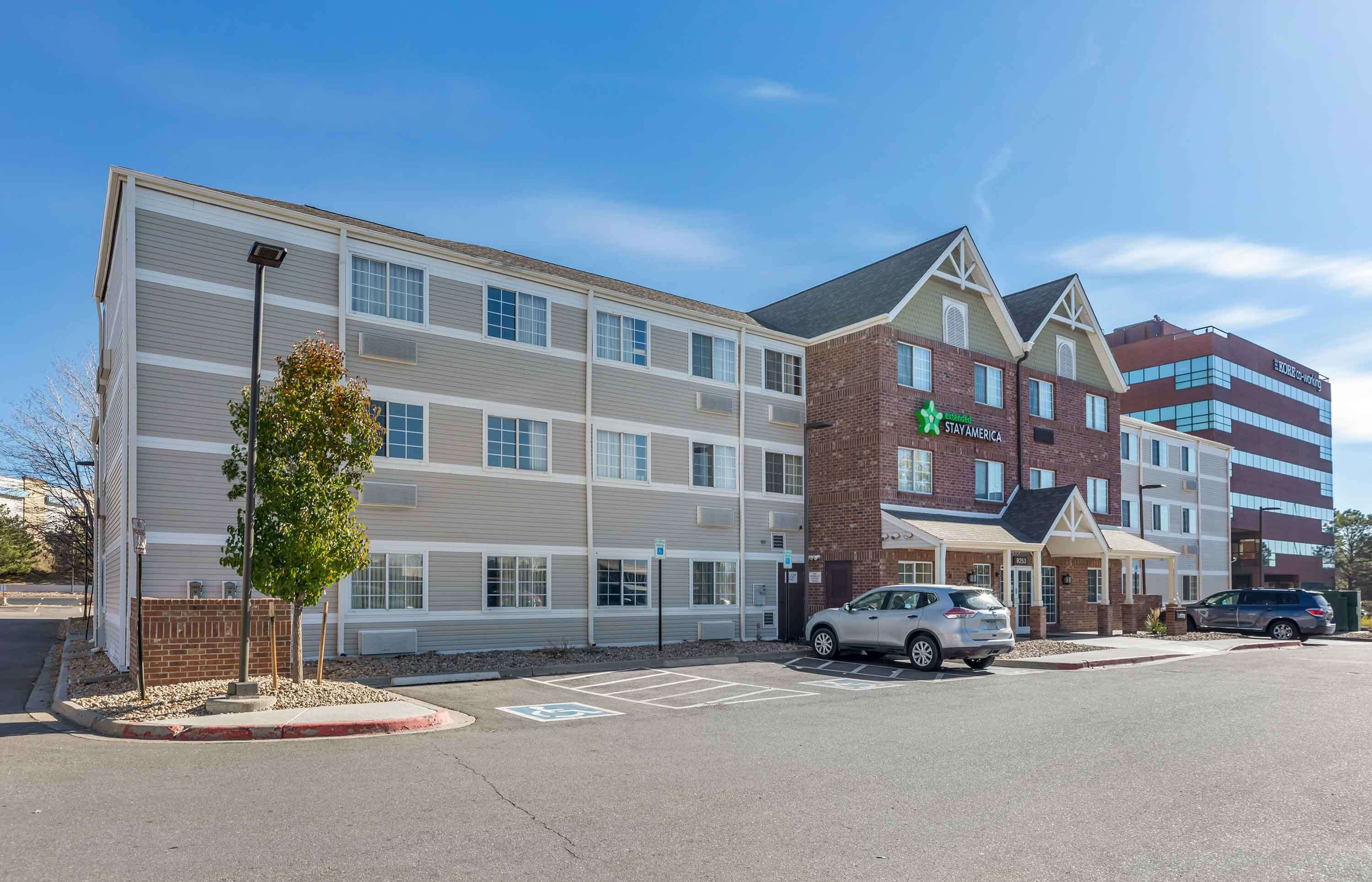 Um hotel Stay America com fachada de tijolos, várias janelas e estacionamento.