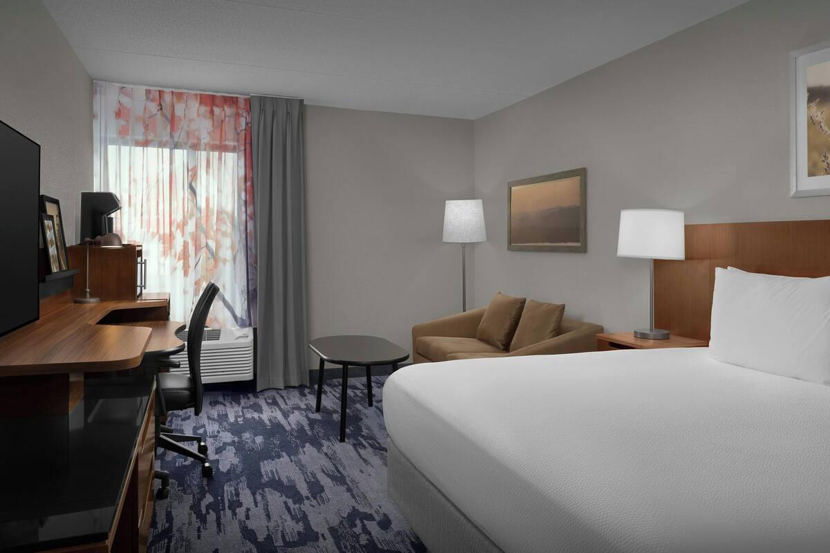 Une chambre d’hôtel avec un grand lit, un bureau avec une chaise, une petite table et un canapé.