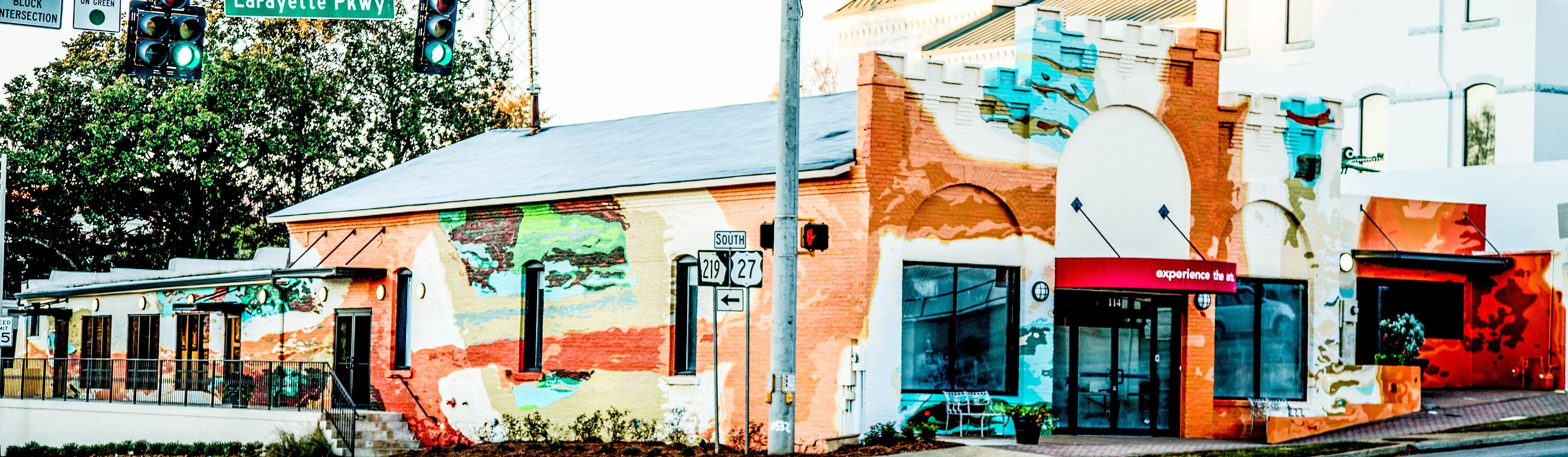 Un edificio con un mural colorido, un cartel que indica Lafayette Pkwy y un escaparate con toldo rojo.