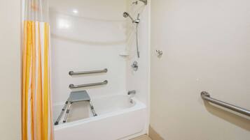 Baño con bañera blanca, ducha y retrete. Cuenta con barras de apoyo para mayor seguridad.