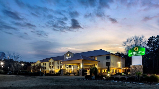 Un La Quinta Inn & Suites con un amplio estacionamiento y una entrada bien iluminada.