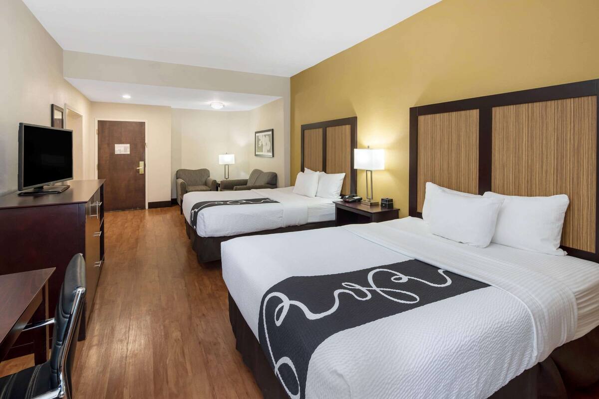Une chambre d’hôtel avec deux lits, une télévision, un bureau et une chaise.