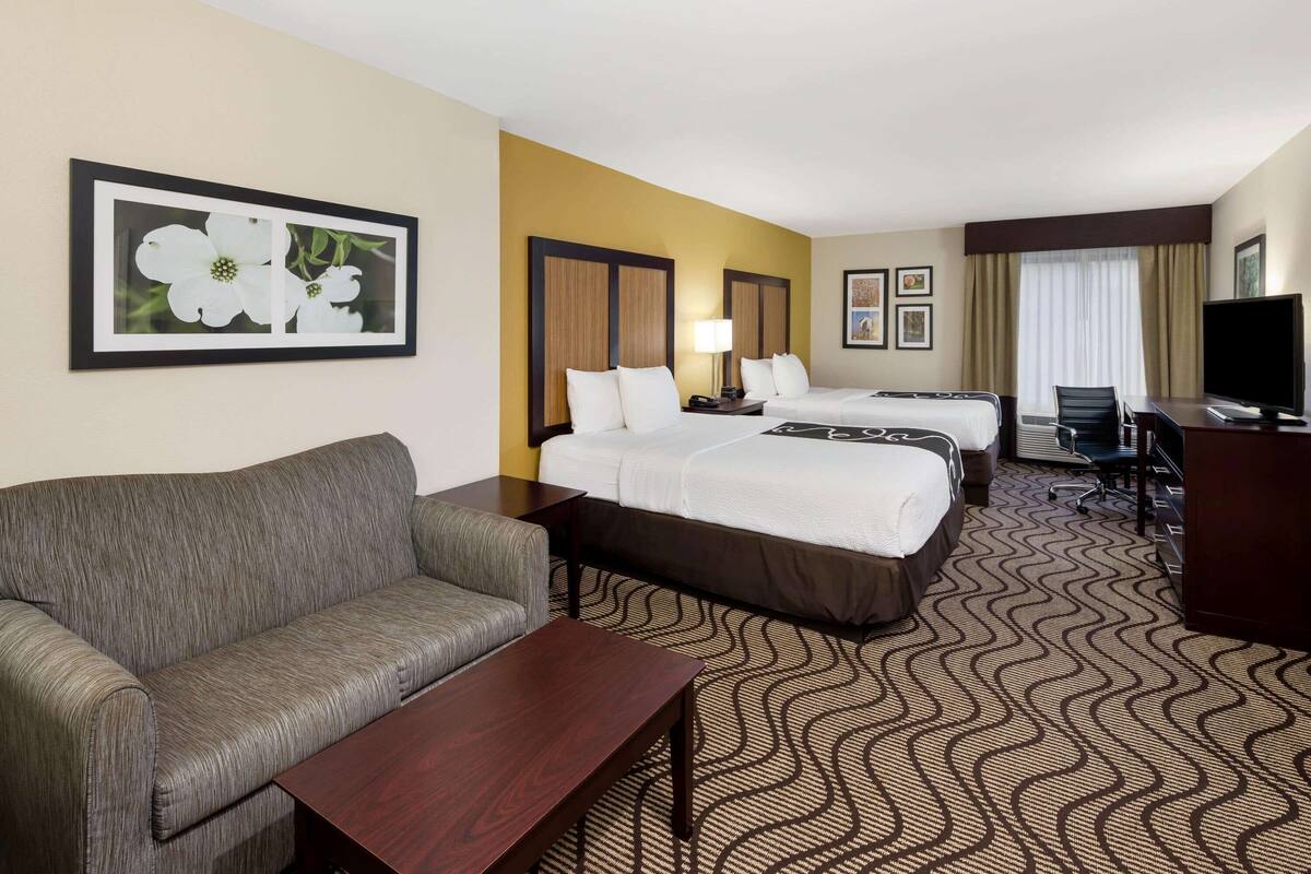 Une chambre d’hôtel avec deux lits, un canapé, un bureau et une télévision.