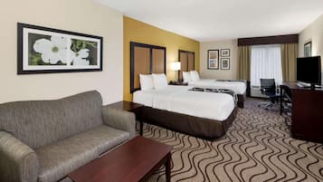 A hotel room with two beds, a sofa, a desk, and a TV.