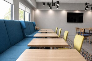 Un comedor moderno con un sofá azul, mesas de madera y sillas amarillas.