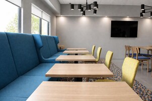Un comedor moderno con un sofá azul, mesas de madera y sillas amarillas.