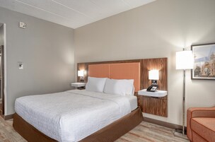 A hotel room with a large bed, a bedside table with a lamp, and a small desk with a phone.
