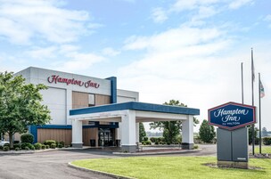 A Hampton Inn hotel with a modern facade, a welcoming entrance, and a clear sky.
