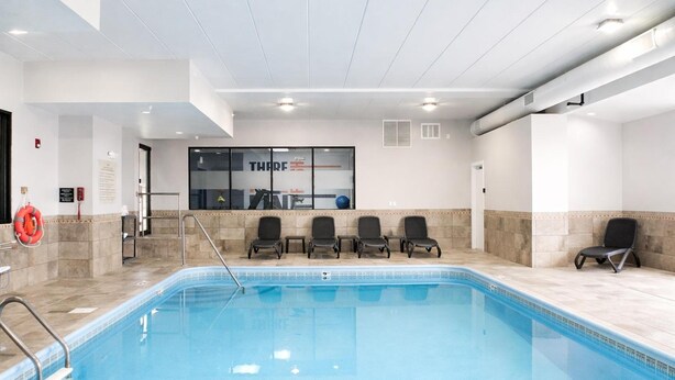 A swimming pool with a glass wall, chairs, and a lifebuoy.
