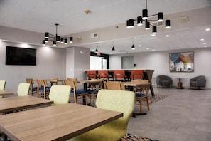 A conference room with multiple tables and chairs, ceiling lights, a flat-screen TV, and a large abstract painting on the wall. - Hampton Inn by Hilton Washington Court House (Jeffersonville)