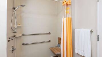 A shower area with a handheld showerhead, grab bars, a wooden bench, and a towel rack.