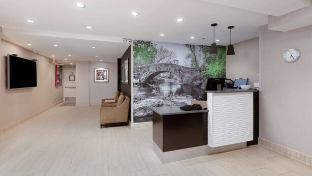 A reception area with a desk, a clock, and a wall-mounted television.