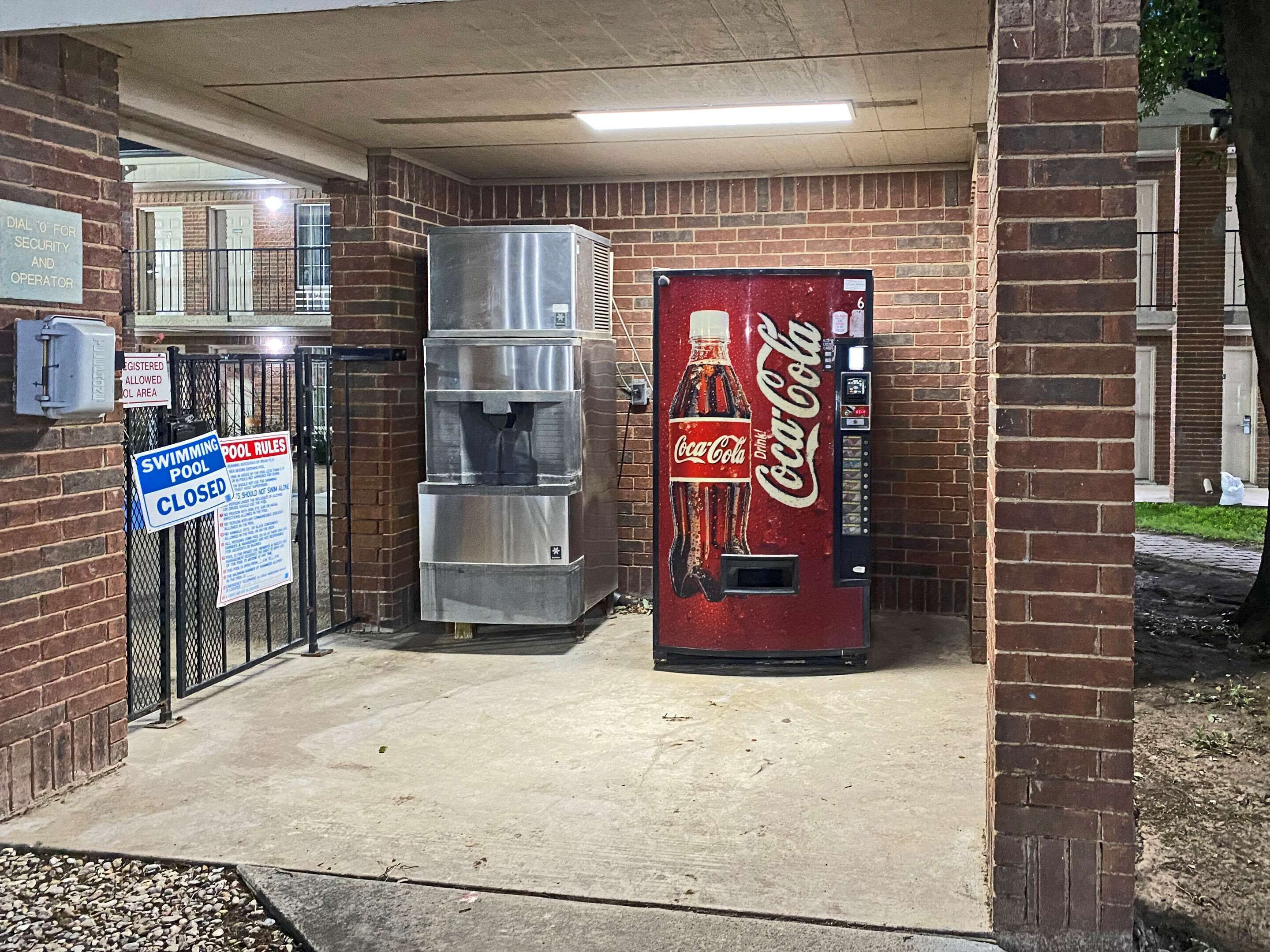 Un distributeur automatique de Coca-Cola, une fontaine à eau et un panneau indiquant que la piscine est fermée.