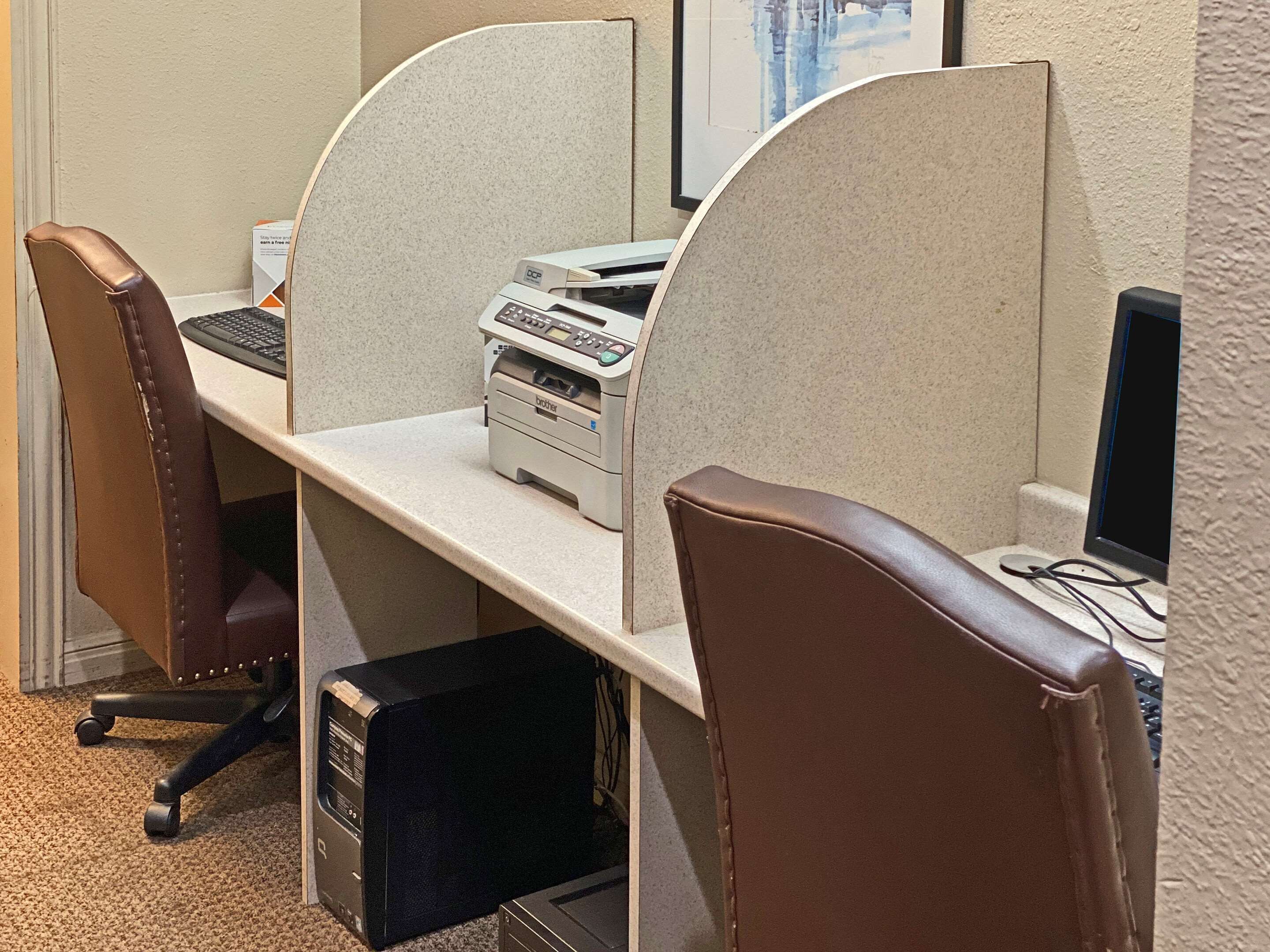 A cubicle with a printer, computer, and chair.