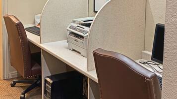 A cubicle with a printer, computer, and chair.