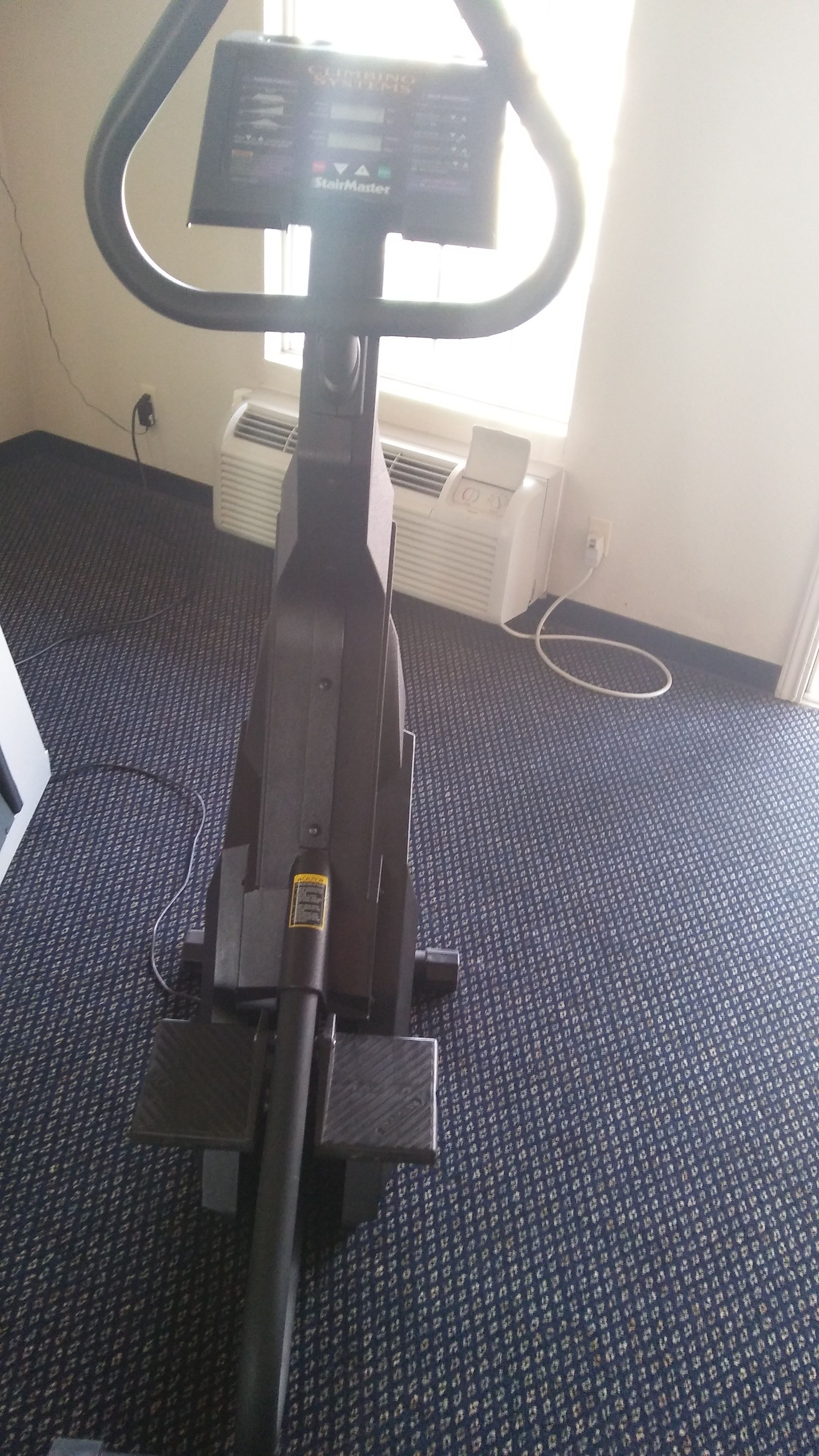 An exercise machine in a room with carpeted flooring and a window.