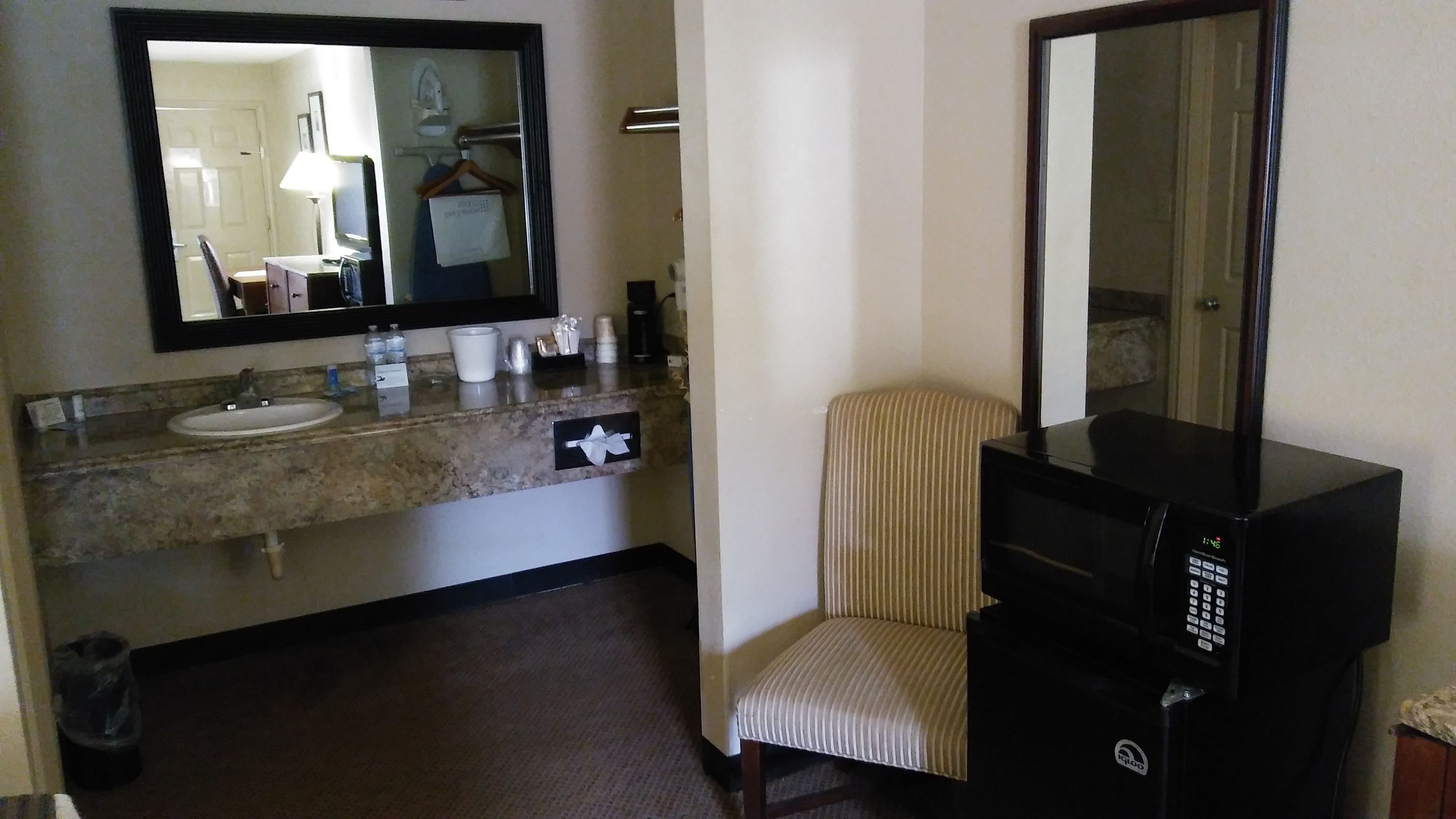 Een hotelbadkamer met een wastafel, spiegel, zeepdispenser en een magnetron.