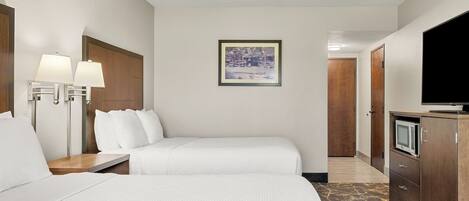 A hotel room with two beds, a TV, a desk, and a framed picture on the wall.