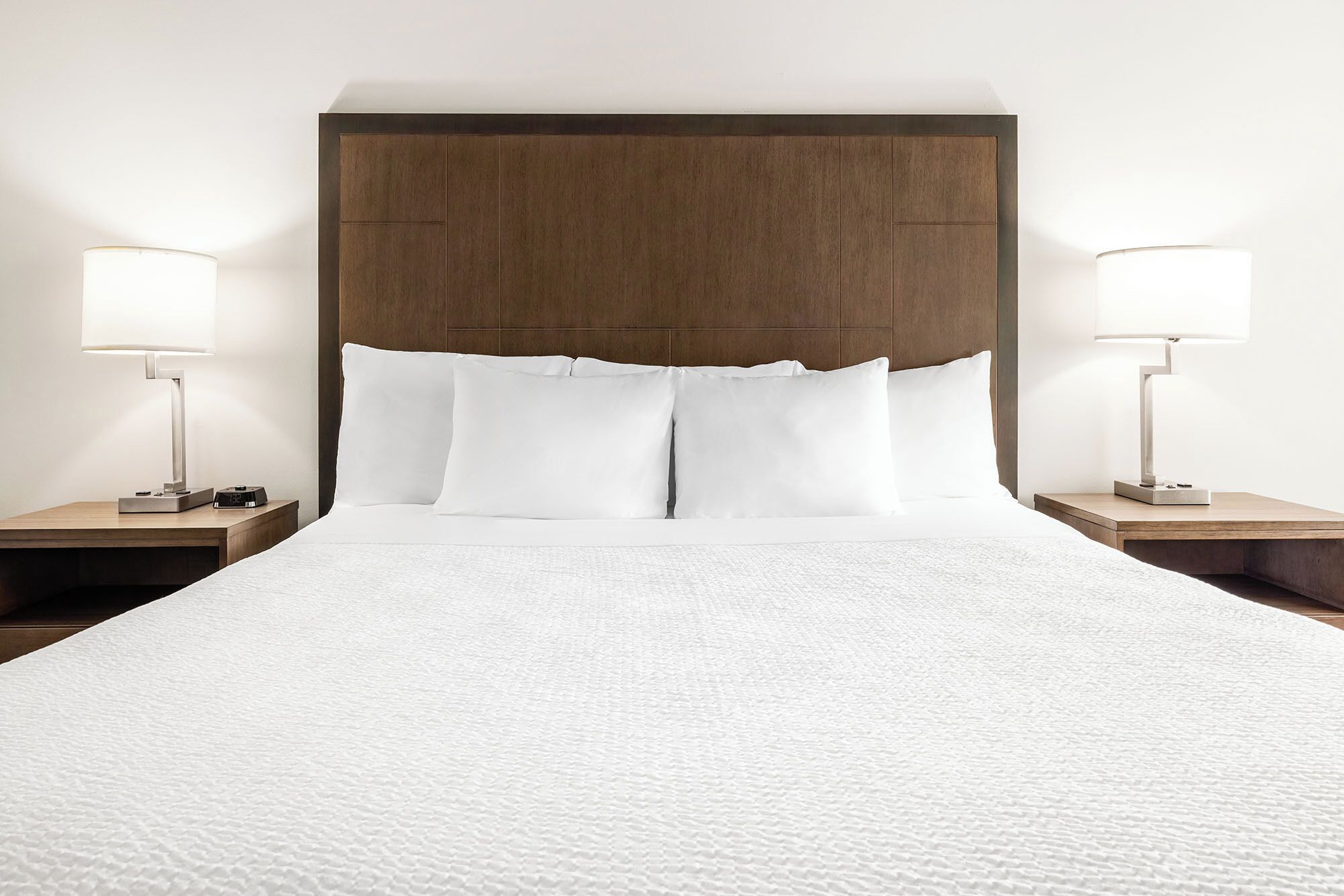 Une chambre d’hôtel avec un grand lit, deux tables de chevet et deux lampes.