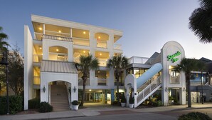 A multi-story hotel with a prominent entrance, a covered outdoor area, and a staircase leading to the upper levels. - Seaside Inn Oceanfront (Isle of Palms)