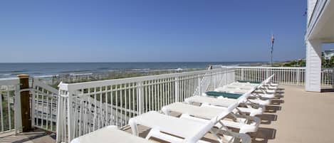 Un balcon avec des balustrades blanches donnant sur une plage.