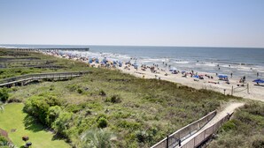 A beach with a wooden boardwalk, umbrellas, and people. - Seaside Inn Oceanfront (Isle of Palms)