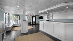 A modern kitchen with white cabinetry, dark flooring, and a large island. - Seaside Inn Oceanfront (Isle of Palms)