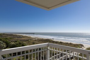 A balcony with a view of a beach and a pier.