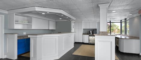 Una cocina moderna con armarios blancos, una isla central y vistas al exterior.