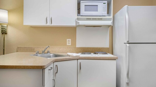 A kitchen with white cabinets, a microwave, a stove, and a sink. - Extended Stay America Suites Washington DC Landover (Upper Marlboro)