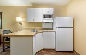 A compact kitchen with white cabinets, a microwave, a refrigerator, and a sink. - Extended Stay America Suites Washington DC Landover (Upper Marlboro)