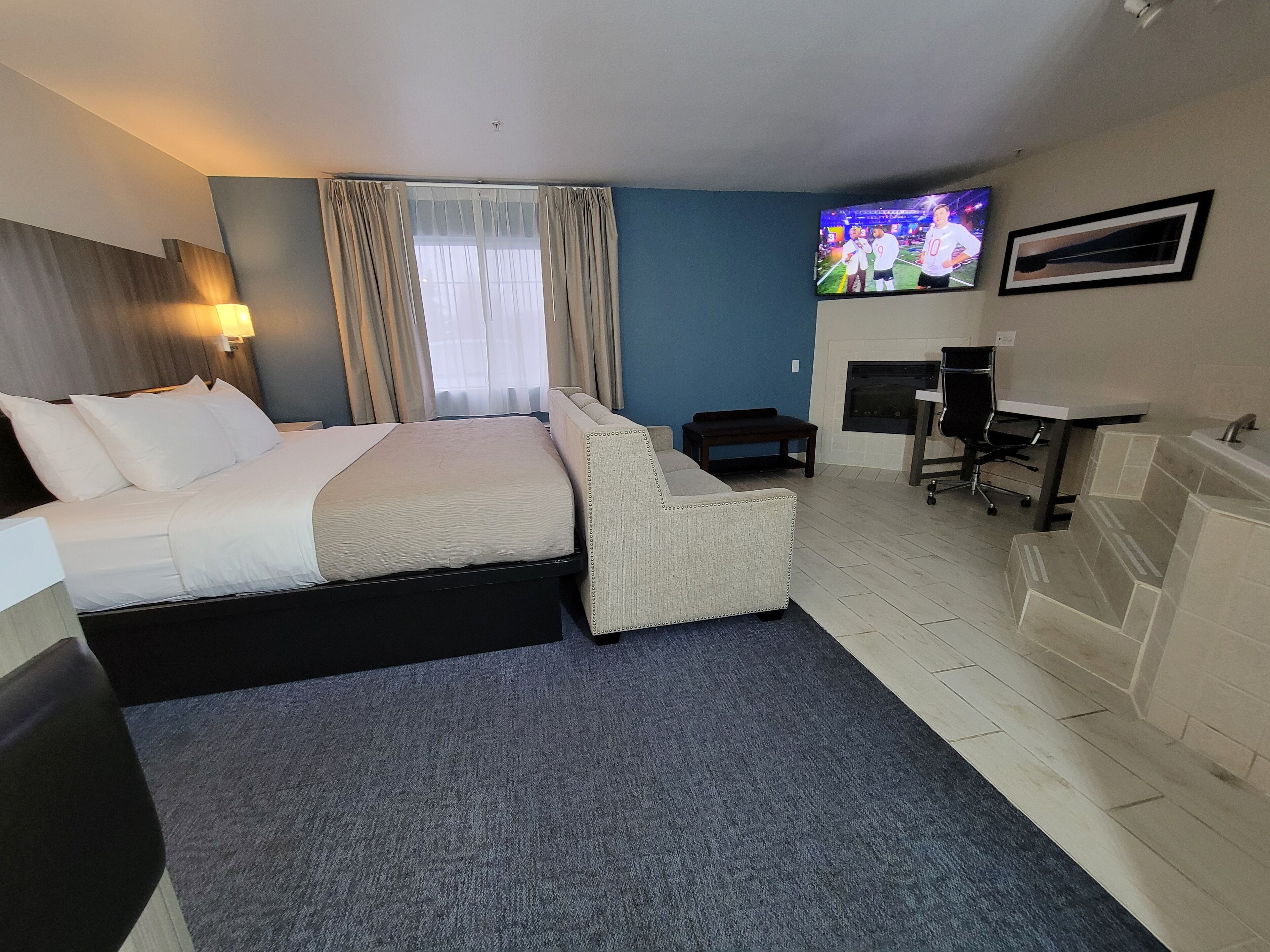 Une chambre d’hôtel équipée d’un lit, d’un bureau, d’une chaise, d’une télévision et d’une cheminée.