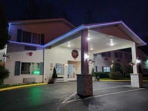 Un hôtel doté d’une entrée couverte, d’une enseigne au néon et d’une couronne de Noël.