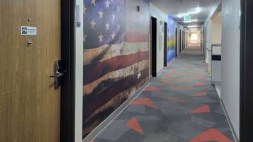 A hallway with a large American flag mural, carpeted floor with red arrows, and doors numbered 217.