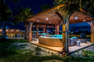 Un espacio de estar techado al aire libre con mobiliario de mimbre y una parrilla.