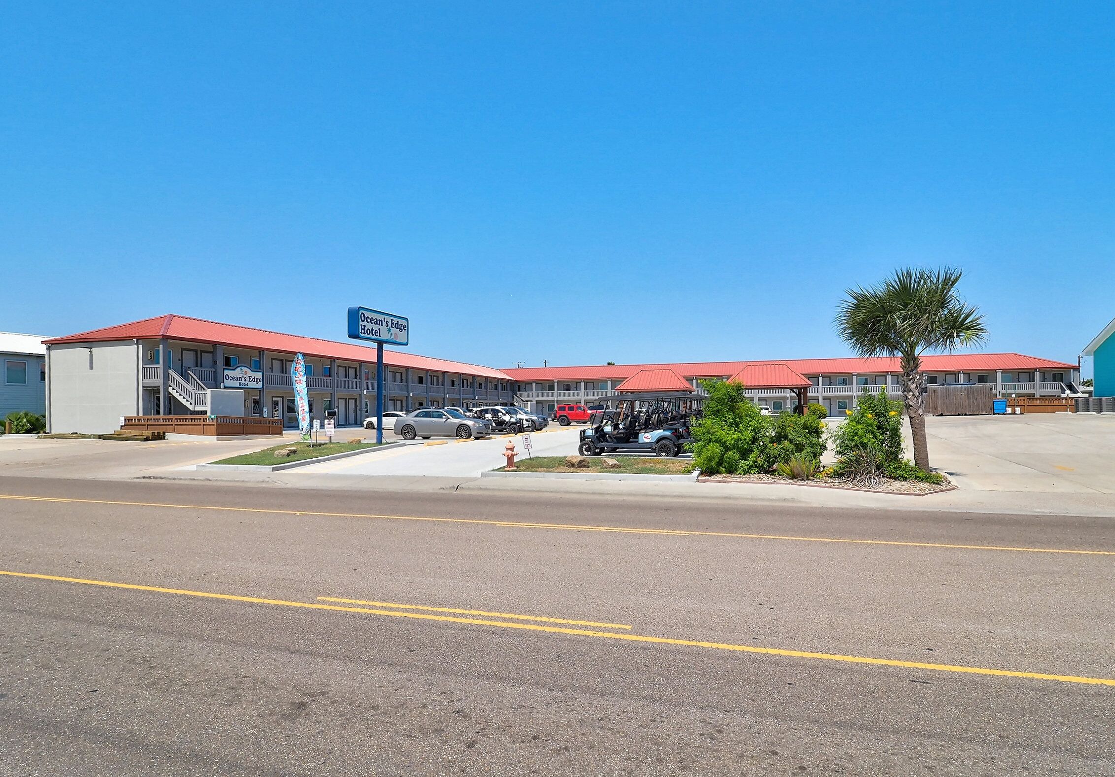 A motel with a red roof and multiple parking spaces.