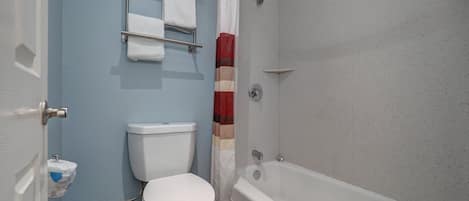 Ein Badezimmer mit Toilette, einer Duschkabine und einem Handtuchhalter mit Handtüchern.