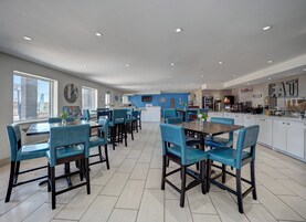 A spacious kitchen with modern appliances, a dining area with blue chairs, and a large window providing a view of the outside.