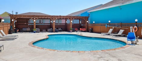 Ein Schwimmbecken mit Liegestühlen und einer Holzpergola.