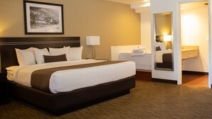 A hotel room with a large bed, a bedside table, a lamp, a framed picture on the wall, and a bathroom visible through an open door. - Villa Motel at Manitou Springs (Manitou Springs)