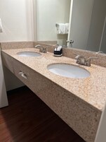 Un baño con dos lavamanos, un espejo y un perchero para toallas.