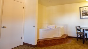 A hotel room with a white door, a bathtub with a towel, a wooden floor, and a chair. - Villa Motel at Manitou Springs (Manitou Springs)
