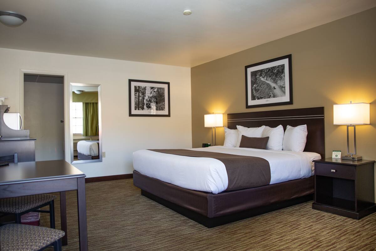 A hotel room with a large bed, bedside lamps, a desk, and a chair.